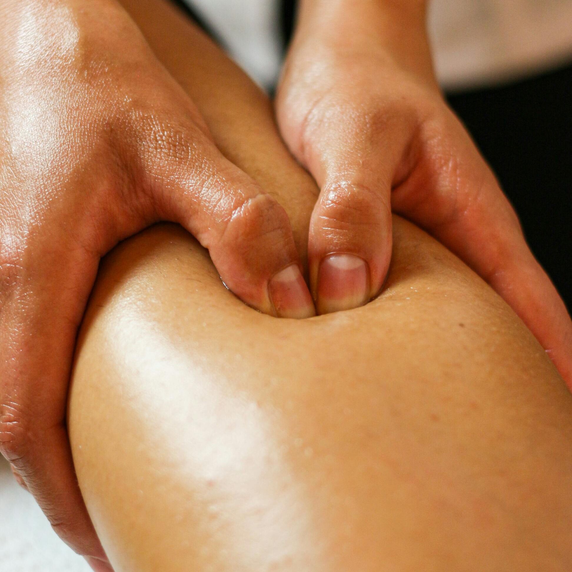 Close-up of hands applying pressure on a leg during a therapeutic massage session.